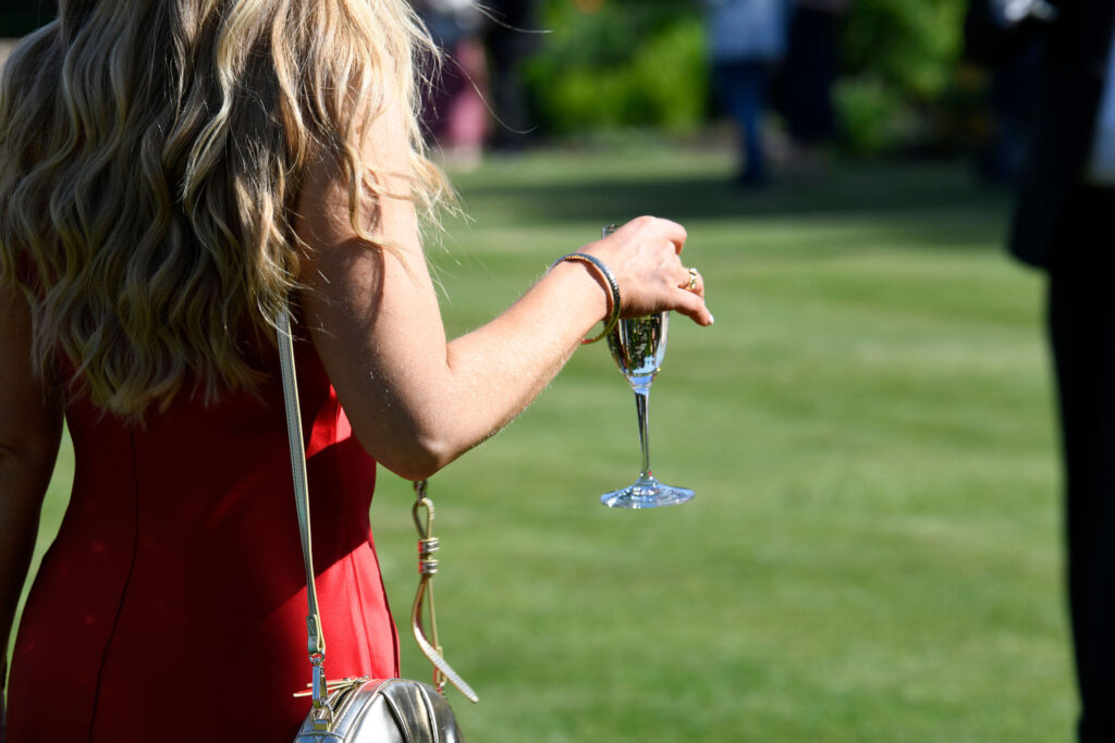 Lady with a glass of English sparkling wine on the lawn