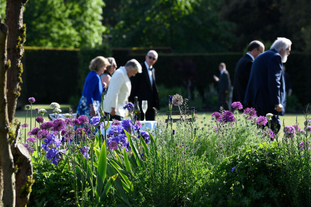 Guests on the lawn at Glyndebourne Opera House beside purple flowers