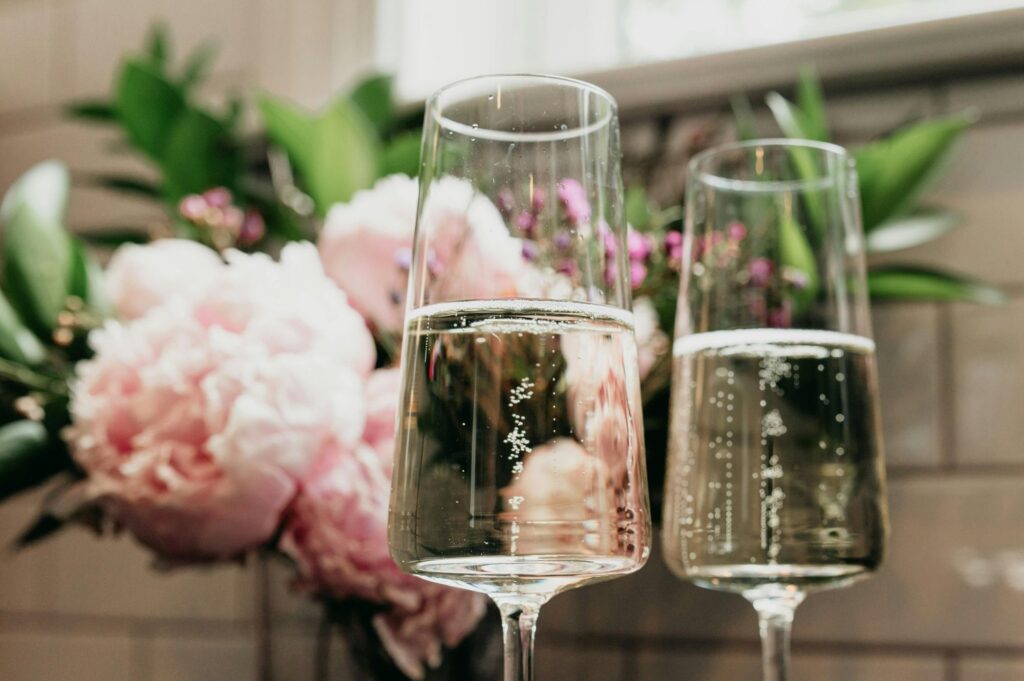 wo glasses of sparkling wine with flower in the background