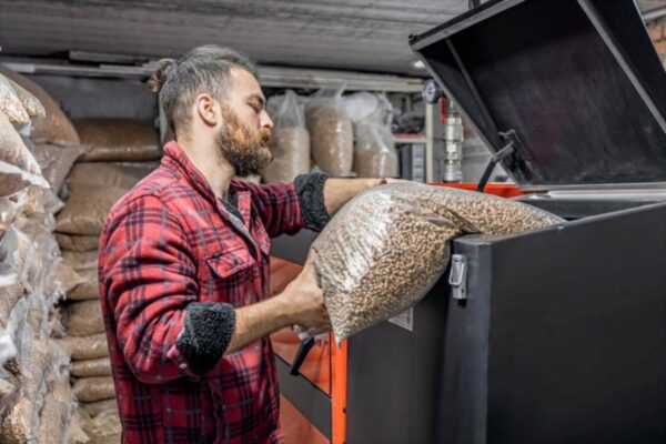 Man loading biofuels boiler with biomass pellets