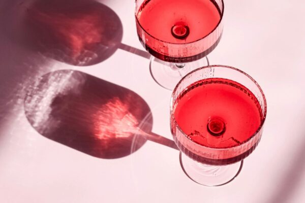 Two coupe glasses of rose wine with pink background