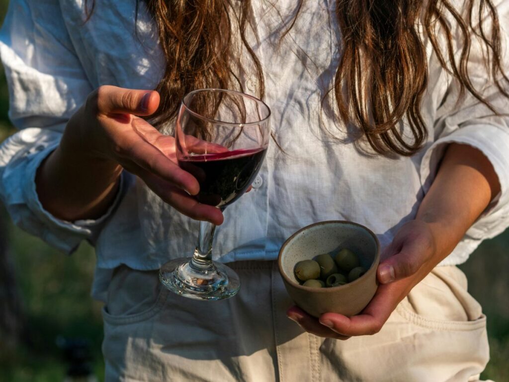 Lady holding a small glass of wine and olives