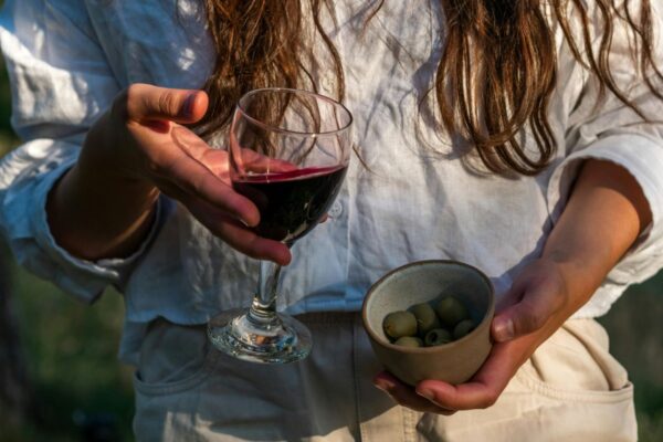 Lady holding a small glass of wine and olives
