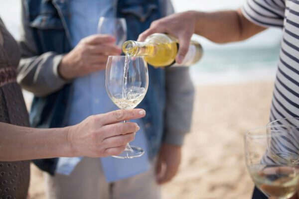 Pouring a bottle of white wine on the beach