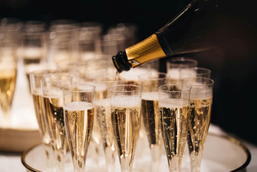 Pouring a bottle of sparkling wine into a tray of flutes