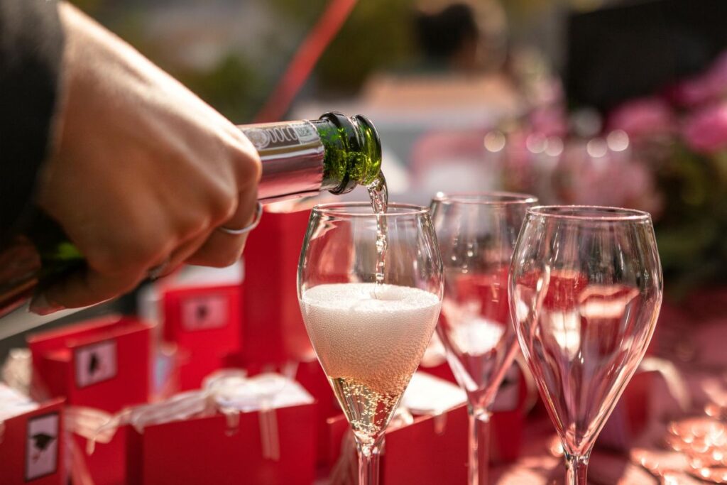 Pouring sparkling wine into wide tulip wine glass