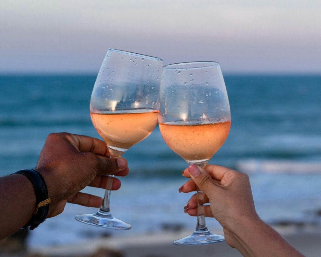 Toasting glasses of rose wine during a sunset at the beach