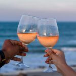 Toasting glasses of rose wine during a sunset at the beach