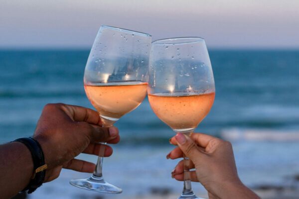 Toasting glasses of rose wine during a sunset at the beach