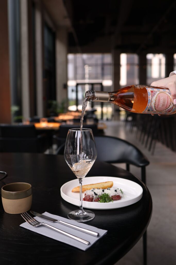 A waiter pouring rose wine at a restaurant table