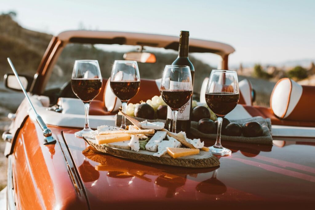 Wine and cheese on the back of a vintage red car