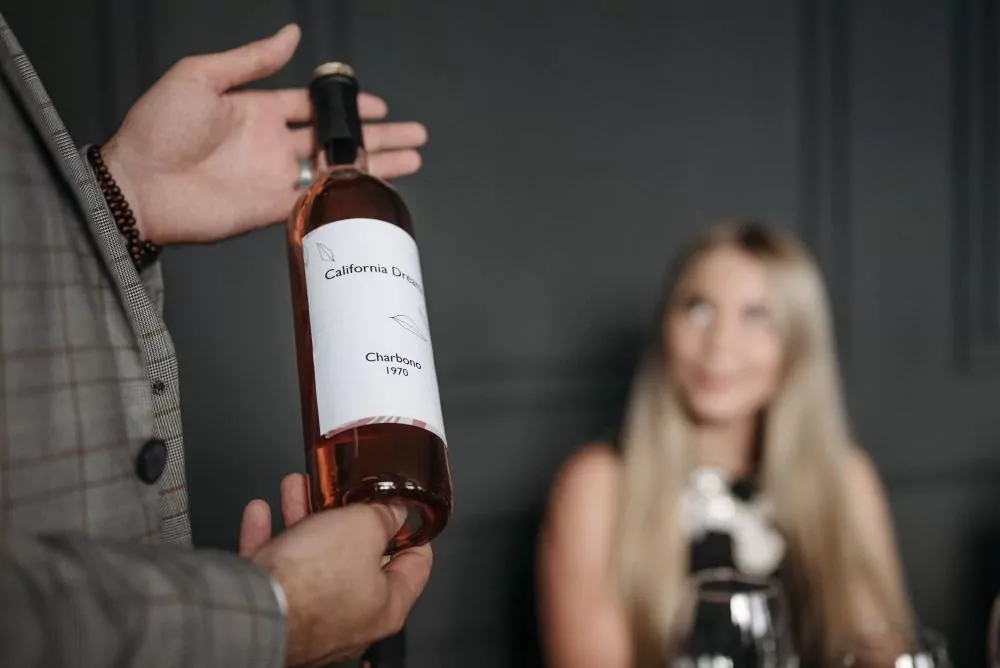 A sommelier presenting a bottle of wine to a wine tasting group