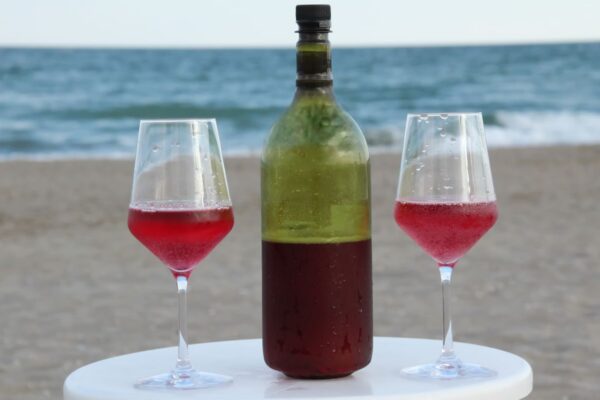 Sparkling red wine with two glasses on the beach