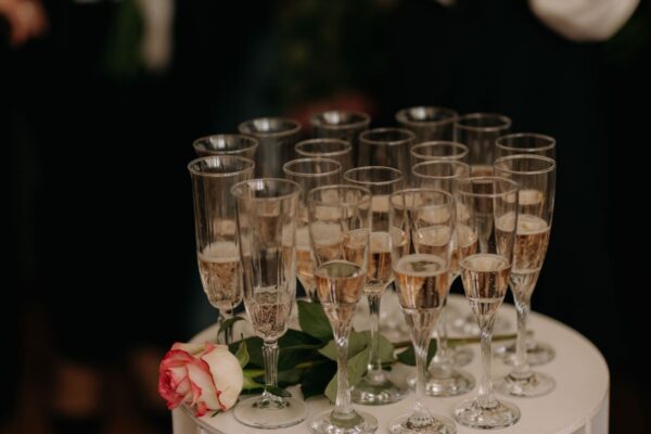 Sparkling rose wine in flutes beside a rose